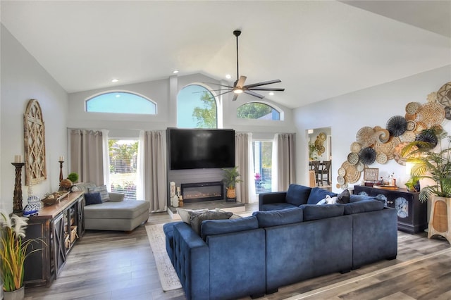 8721 Latham Ln, Hudson, FL 34667 - living room with wood finished floors, a glass covered fireplace, a ceiling fan, high vaulted ceiling, and recessed lighting