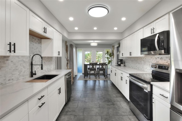 8721 Latham Ln, Hudson, FL 34667 - kitchen with appliances with stainless steel finishes, a sink, white cabinets, backsplash, and light stone counters