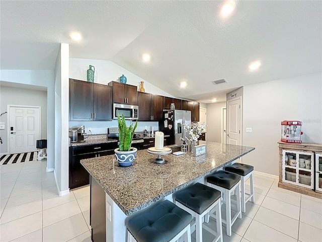 2929 Flying Blackbird Rd, Bartow, FL 33830 - kitchen with stainless steel appliances, vaulted ceiling, a breakfast bar area, light tile patterned flooring, and a center island with sink