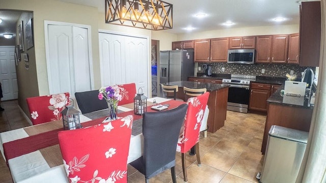 2170 Forest Lake Ave, Dundee, FL 33838 - kitchen featuring appliances with stainless steel finishes, dark countertops, decorative backsplash, light tile patterned floors, and a center island