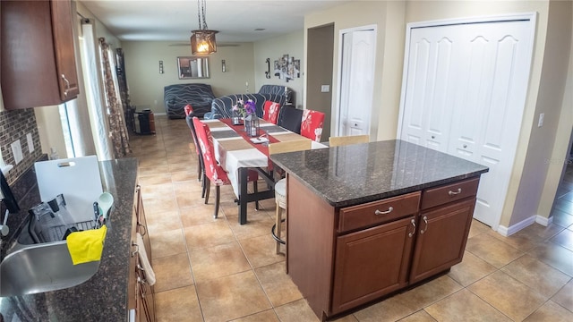 2170 Forest Lake Ave, Dundee, FL 33838 - kitchen featuring open floor plan, a kitchen island, light tile patterned floors, hanging light fixtures, and dark stone counters