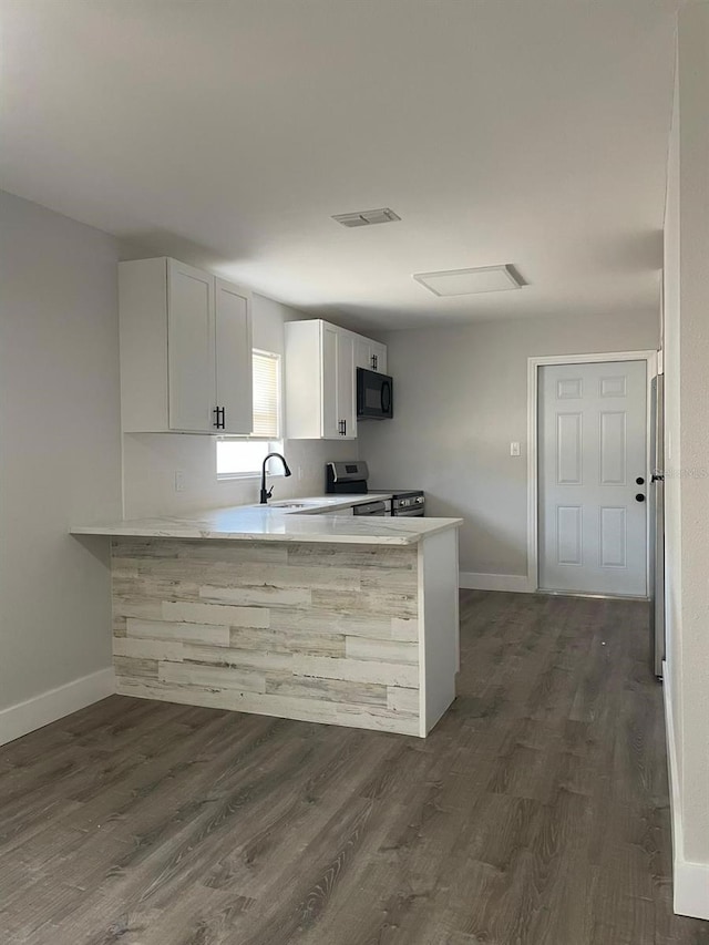 854 Shirley Ann Trl Unit 854/856, Lakeland, FL 33809 - kitchen featuring stainless steel appliances, a peninsula, dark wood-type flooring, and light countertops