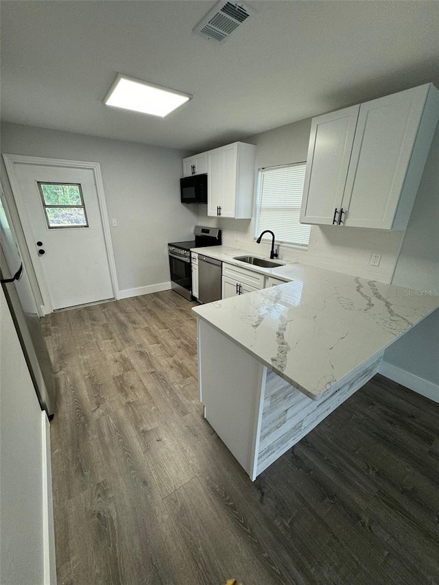 854 Shirley Ann Trl Unit 854/856, Lakeland, FL 33809 - kitchen featuring stainless steel appliances, a sink, dark wood-style flooring, white cabinets, and a peninsula