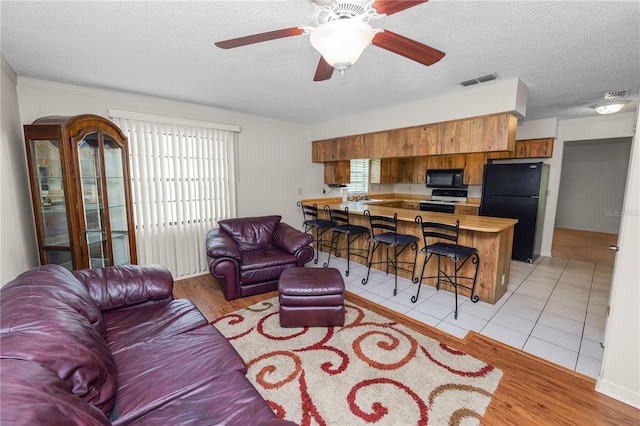 1917 Lori Ln W, Lakeland, FL 33801 - living room with healthy amount of natural light, a textured ceiling, ceiling fan, and light wood-type flooring