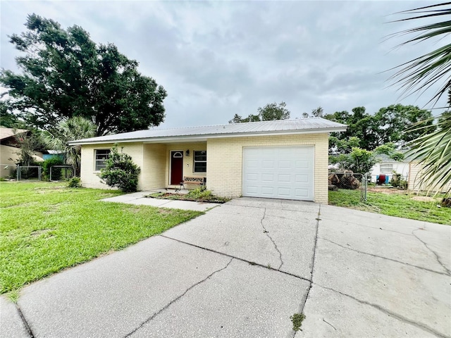355 Pico Ct, Lakeland, FL 33809 - view of front facade with brick siding, a garage, driveway, a front yard, and metal roof