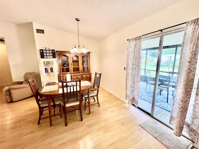 355 Pico Ct, Lakeland, FL 33809 - dining space featuring vaulted ceiling, light wood-style flooring, a textured ceiling, a chandelier, and baseboards