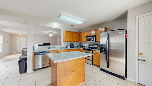 7337 Hunters Greene Cir, Lakeland, FL 33810 - kitchen with appliances with stainless steel finishes, a kitchen island, light countertops, light tile patterned flooring, and a sink
