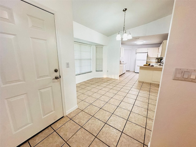 709 N Polk Ave, Fort Meade, FL 33841 - kitchen featuring freestanding refrigerator, light tile patterned flooring, vaulted ceiling, white cabinetry, and a chandelier