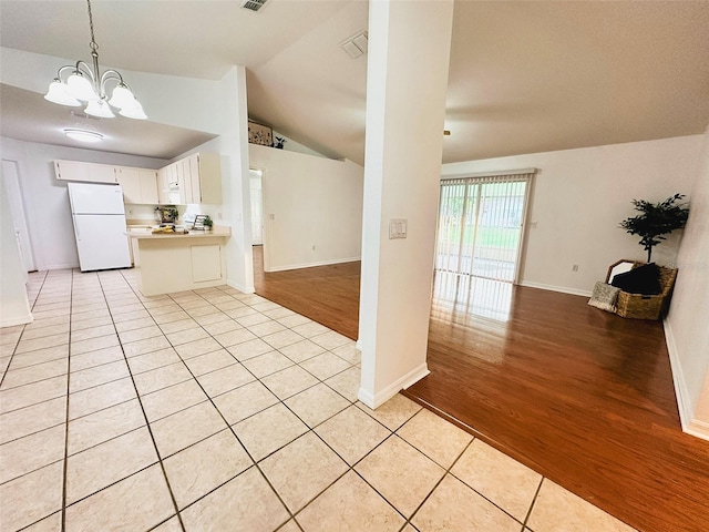 709 N Polk Ave, Fort Meade, FL 33841 - kitchen with freestanding refrigerator, open floor plan, a chandelier, light countertops, and vaulted ceiling