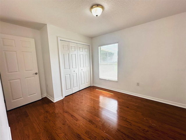 709 N Polk Ave, Fort Meade, FL 33841 - unfurnished bedroom with baseboards, dark wood-style flooring, a closet, and a textured ceiling