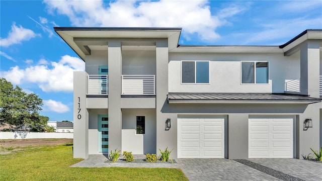 1170 Windjammer Dr, Lakeland, FL 33803 - view of front facade with a standing seam roof, a garage, stucco siding, decorative driveway, and a balcony