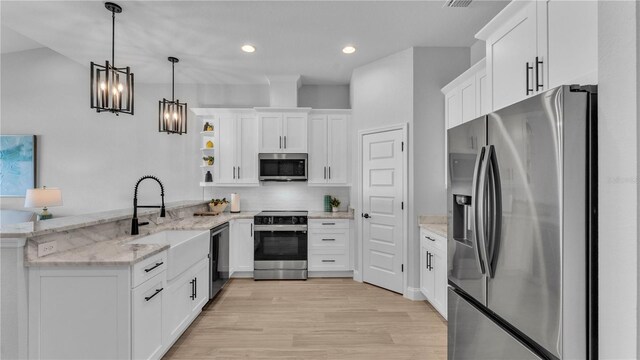 1172 Windjammer Dr, Lakeland, FL 33803 - kitchen featuring appliances with stainless steel finishes, a peninsula, open shelves, white cabinets, and decorative light fixtures