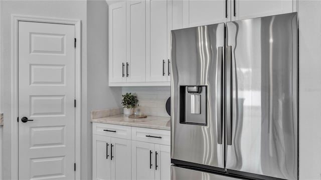 1172 Windjammer Dr, Lakeland, FL 33803 - kitchen with stainless steel fridge, backsplash, white cabinets, and light stone counters
