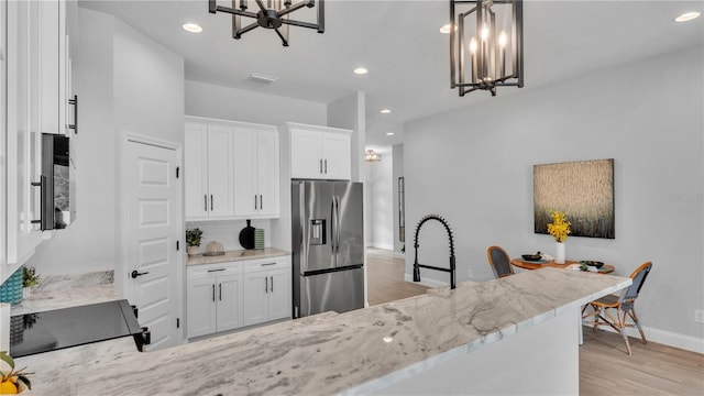 1172 Windjammer Dr, Lakeland, FL 33803 - kitchen featuring stainless steel fridge with ice dispenser, a chandelier, light stone counters, light wood-type flooring, and stove