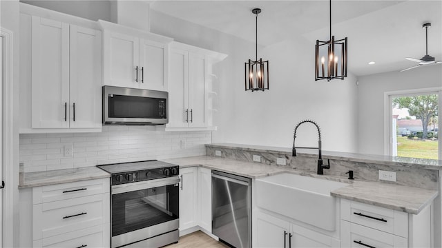 1172 Windjammer Dr, Lakeland, FL 33803 - kitchen featuring appliances with stainless steel finishes, a peninsula, tasteful backsplash, white cabinetry, and light stone countertops