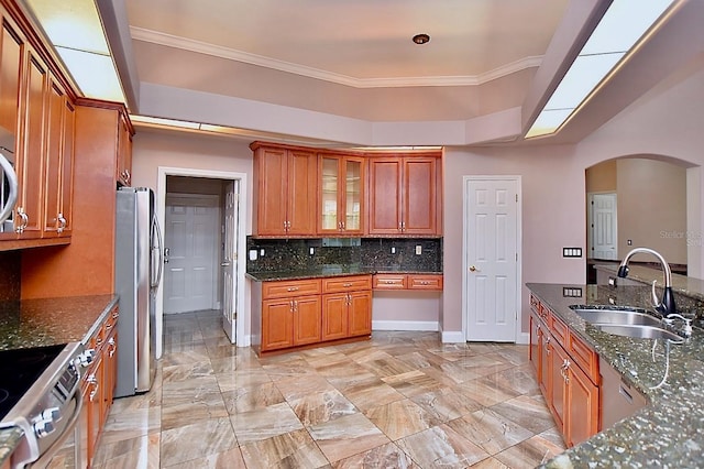 943 Hamilton Place Ln, Lakeland, FL 33813 - kitchen with appliances with stainless steel finishes, arched walkways, decorative backsplash, dark stone countertops, and crown molding