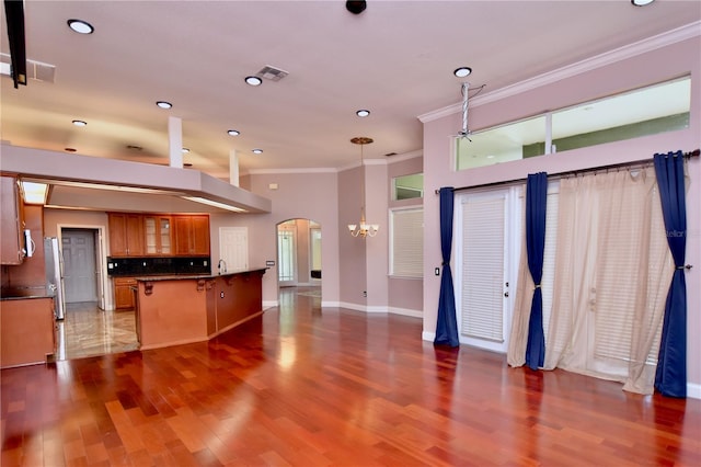 943 Hamilton Place Ln, Lakeland, FL 33813 - kitchen featuring brown cabinetry, crown molding, a breakfast bar area, a chandelier, and tasteful backsplash
