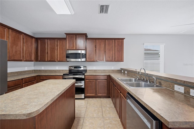 6819 Glenbrook Dr, Lakeland, FL 33811 - kitchen featuring appliances with stainless steel finishes, a sink, a peninsula, light tile patterned floors, and a center island