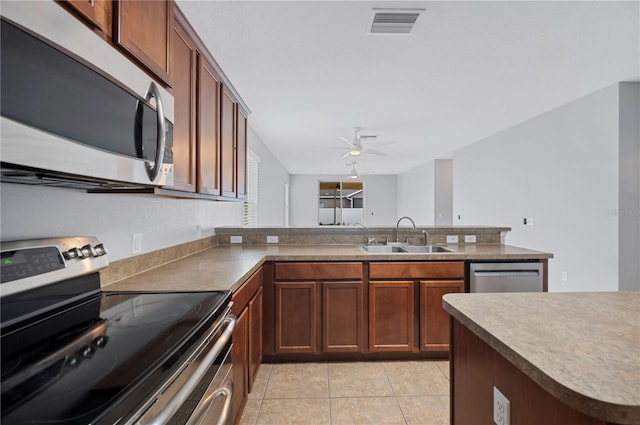 6819 Glenbrook Dr, Lakeland, FL 33811 - kitchen with stainless steel appliances, a sink, a ceiling fan, light tile patterned floors, and a peninsula