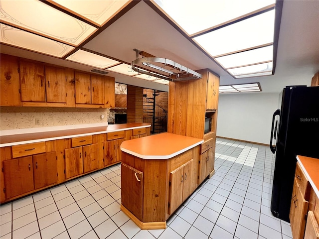 8504 N Campbell Rd, Lakeland, FL 33810 - kitchen featuring black appliances, brown cabinetry, light tile patterned flooring, light countertops, and a peninsula