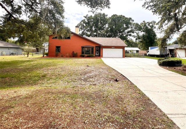 8504 N Campbell Rd, Lakeland, FL 33810 - view of side of property featuring concrete driveway, an attached garage, and a chimney