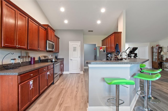 1531 Blue Sky Blvd, Haines City, FL 33844 - kitchen featuring stainless steel appliances, a peninsula, light wood finished floors, a breakfast bar, and dark countertops