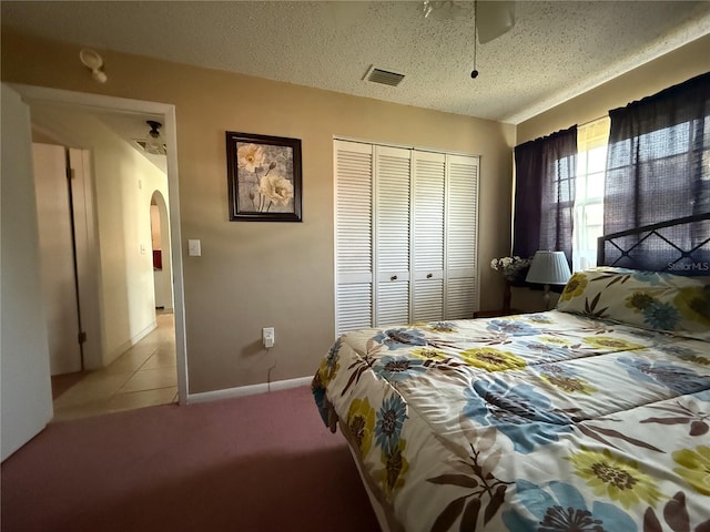 2424 Bates Ave SW, Winter Haven, FL 33880 - bedroom with arched walkways, a closet, light carpet, light tile patterned floors, and a textured ceiling