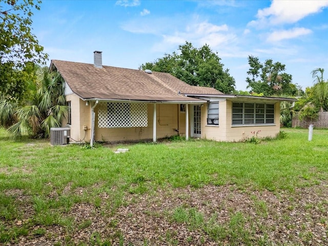 320 W Carver St, Lakeland, FL 33805 - rear view of property with concrete block siding, a shingled roof, a chimney, a lawn, and central air condition unit