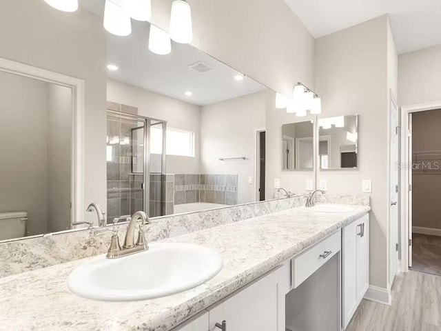 828 Cypress Creek Run, Saint Cloud, FL 34771 - bathroom featuring a stall shower, double vanity, a garden tub, toilet, and wood finished floors
