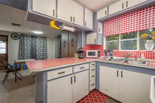 114 Pennsylvania Ave, Wauchula, FL 33873 - kitchen with white microwave, a peninsula, light countertops, white cabinets, and backsplash