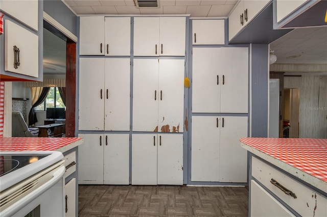 114 Pennsylvania Ave, Wauchula, FL 33873 - kitchen featuring light countertops, white cabinets, a drop ceiling, and wood walls