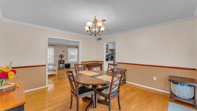 1910 Clubhouse Rd, Lakeland, FL 33813 - dining room featuring light wood-style flooring, a chandelier, crown molding, a textured ceiling, and baseboards