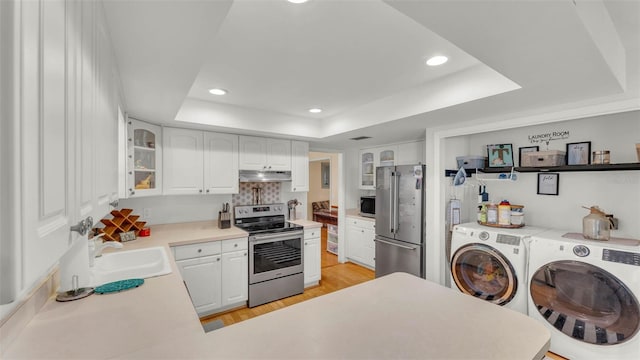 1910 Clubhouse Rd, Lakeland, FL 33813 - kitchen with appliances with stainless steel finishes, washer and dryer, under cabinet range hood, a raised ceiling, and a sink