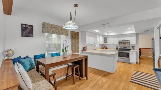 1910 Clubhouse Rd, Lakeland, FL 33813 - kitchen featuring stainless steel electric range oven, under cabinet range hood, a raised ceiling, light wood-style flooring, and white cabinetry