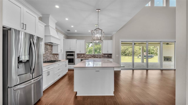 1385 Ewell Rd, Lakeland, FL 33811 - kitchen with stainless steel appliances, backsplash, light countertops, white cabinetry, and a kitchen island