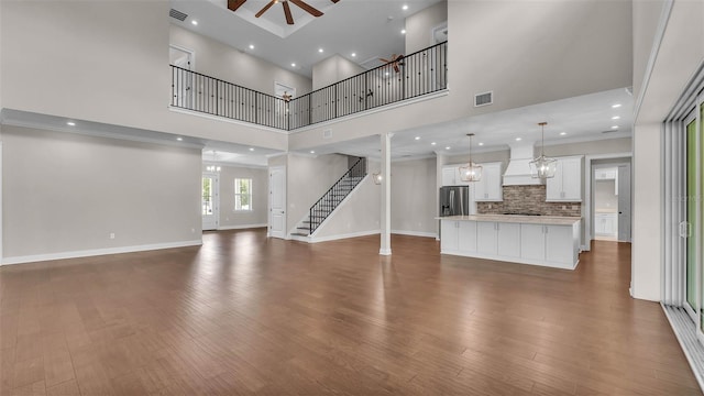 1385 Ewell Rd, Lakeland, FL 33811 - unfurnished living room featuring a towering ceiling, wood finished floors, stairs, ceiling fan, and recessed lighting