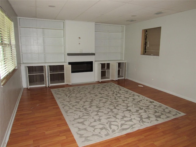 1440 Hackl Blvd, Bartow, FL 33830 - living room featuring wood finished floors, built in shelves, baseboards, a glass covered fireplace, and a paneled ceiling