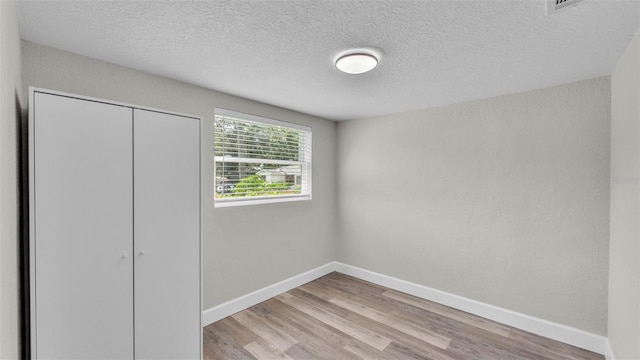 980 S Mill Ave, Bartow, FL 33830 - unfurnished bedroom featuring light wood-style floors, a textured ceiling, and a closet