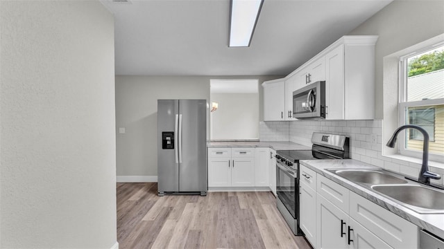 980 S Mill Ave, Bartow, FL 33830 - kitchen with stainless steel appliances, tasteful backsplash, white cabinetry, light wood-style floors, and light countertops