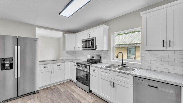 980 S Mill Ave, Bartow, FL 33830 - kitchen with stainless steel appliances, light wood finished floors, white cabinetry, backsplash, and light stone countertops