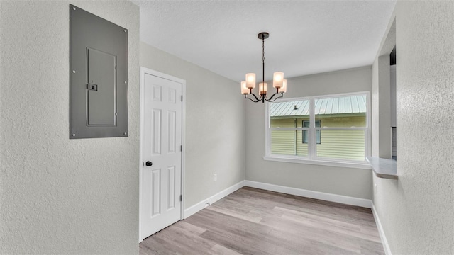 980 S Mill Ave, Bartow, FL 33830 - empty room with electric panel, a textured wall, a chandelier, and wood finished floors