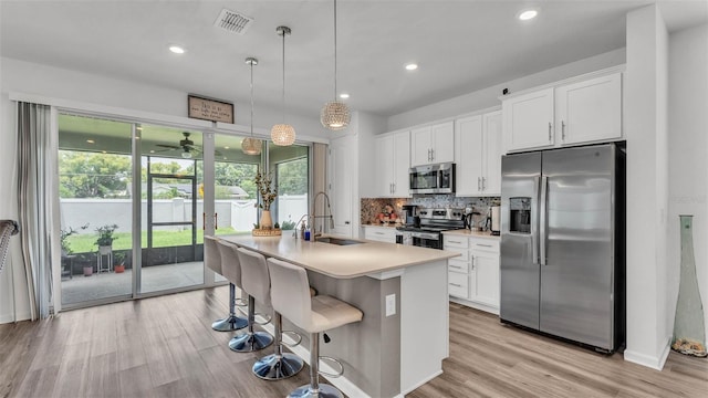 1125 Mattie Pointe Blvd, Auburndale, FL 33823 - kitchen with appliances with stainless steel finishes, decorative backsplash, white cabinetry, a kitchen island with sink, and recessed lighting
