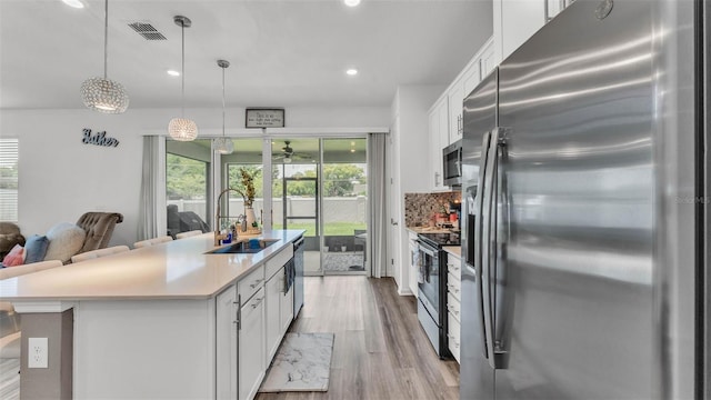 1125 Mattie Pointe Blvd, Auburndale, FL 33823 - kitchen featuring appliances with stainless steel finishes, white cabinetry, light wood-style flooring, recessed lighting, and decorative backsplash