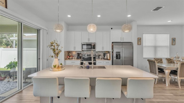 1125 Mattie Pointe Blvd, Auburndale, FL 33823 - kitchen featuring appliances with stainless steel finishes, light wood-style floors, white cabinets, tasteful backsplash, and recessed lighting