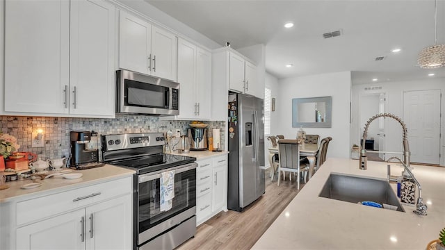 1125 Mattie Pointe Blvd, Auburndale, FL 33823 - kitchen with appliances with stainless steel finishes, backsplash, light countertops, white cabinetry, and light wood finished floors