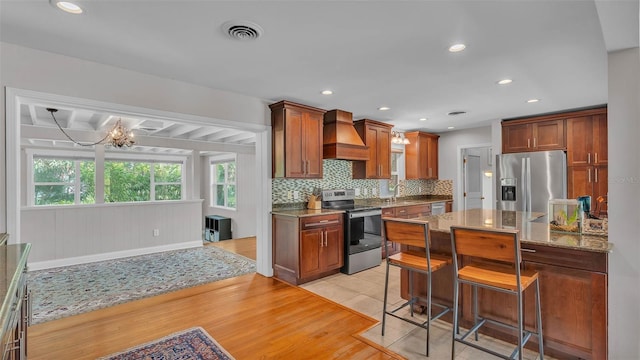 4219 Forest Hills Dr, Lakeland, FL 33813 - kitchen featuring stainless steel appliances, custom exhaust hood, decorative backsplash, a chandelier, and a kitchen bar