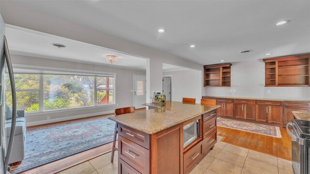 4219 Forest Hills Dr, Lakeland, FL 33813 - kitchen with open shelves, stainless steel appliances, light stone counters, brown cabinets, and light tile patterned flooring