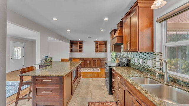 4219 Forest Hills Dr, Lakeland, FL 33813 - kitchen featuring stainless steel electric range, premium range hood, open shelves, a breakfast bar area, and brown cabinetry