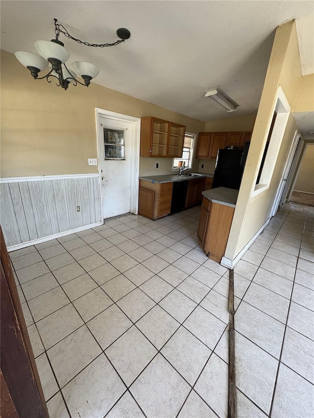 1120 Ivy Ln, Bartow, FL 33830 - kitchen featuring black appliances, a chandelier, light tile patterned floors, a sink, and wainscoting