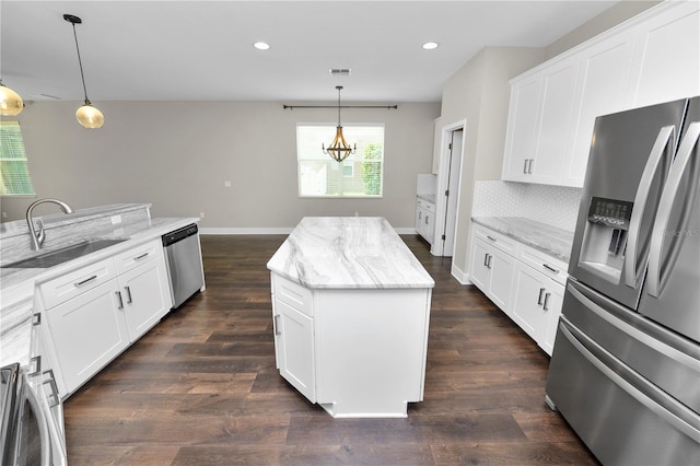 228 Magneta Loop, Auburndale, FL 33823 - kitchen featuring stainless steel appliances, a kitchen island, dark wood-style flooring, decorative light fixtures, and light stone counters